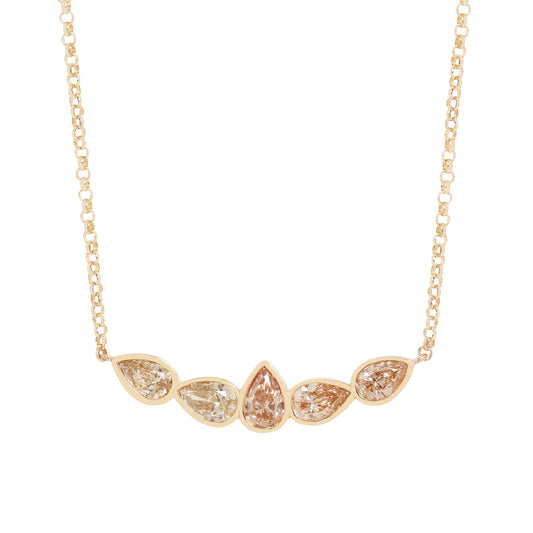 A gold necklace featuring five pear-cut clear gemstones in a row, with the center stone being teardrop-shaped. The stones are set in a yellow gold chain on a solid white background.