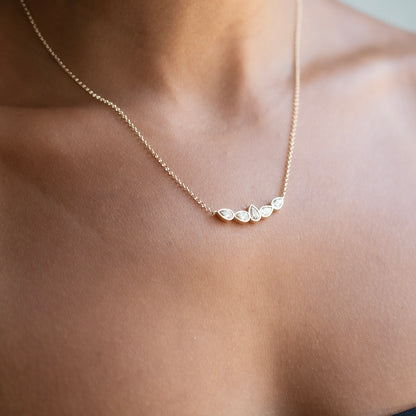 A delicate gold chain necklace with five small champagne diamonds worn on a model's neck.