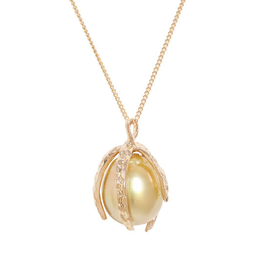 A gold pendant necklace featuring a large, lustrous yellow pearl nestled within a textured gold shell-like setting, suspended from a delicate gold chain against a solid white background.
