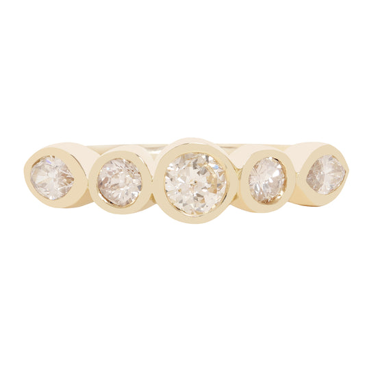 A gold band ring featuring five bezel-set round diamonds of varying sizes, presented on a clean white background.