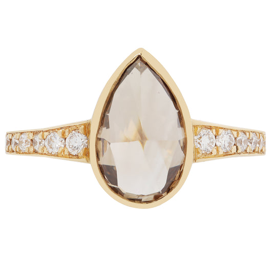 Gold ring with a large teardrop-shaped gemstone and smaller diamonds on a white background