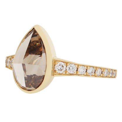 Gold ring with a large brown gemstone and smaller diamonds on a white background