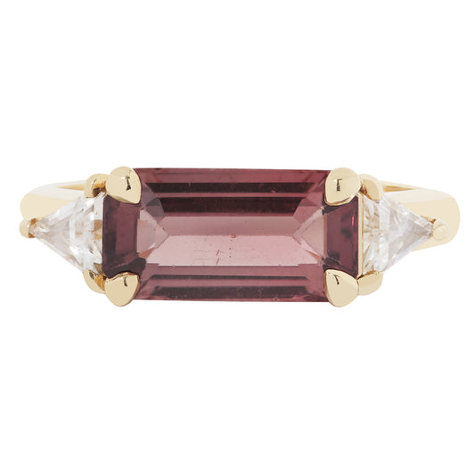 Gold ring with a maroon gemstone and clear stones on a white background
