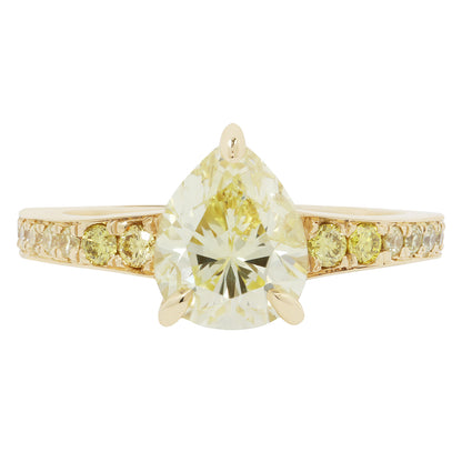 Gold ring with a large pear-shaped yellow diamond and smaller diamonds on the band against a white background