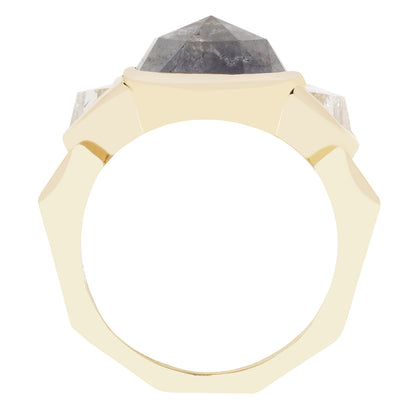 A geometric octagonal ring featuring a faceted dark gray diamond stone in a gold setting, flanked by two clear round-cut stones on a plain white background.