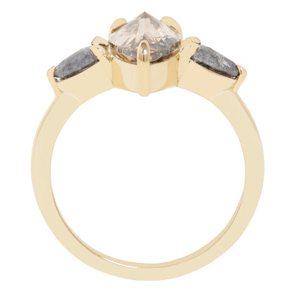 A gold ring featuring a large pear-cut clear diamond with inclusions, accented by two smaller marquise-cut gray diamonds on either side, shown on a plain white background.