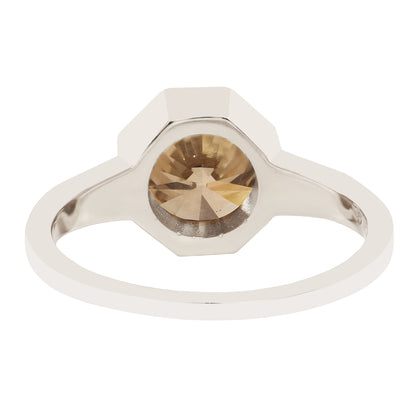 A white gold ring featuring a faceted, octagonal bezel-set round diamond with a warm champagne-gold color, shown against a plain white background.