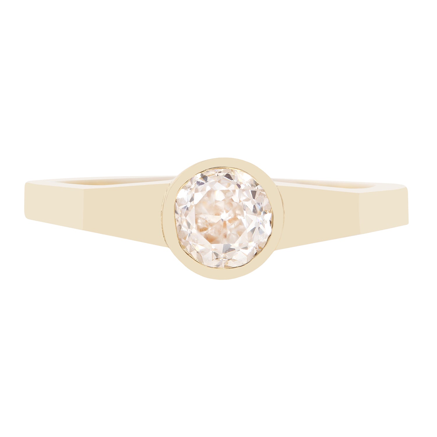 A minimalist yellow gold ring featuring a bezel-set round-cut clear diamond, presented on a solid white background.