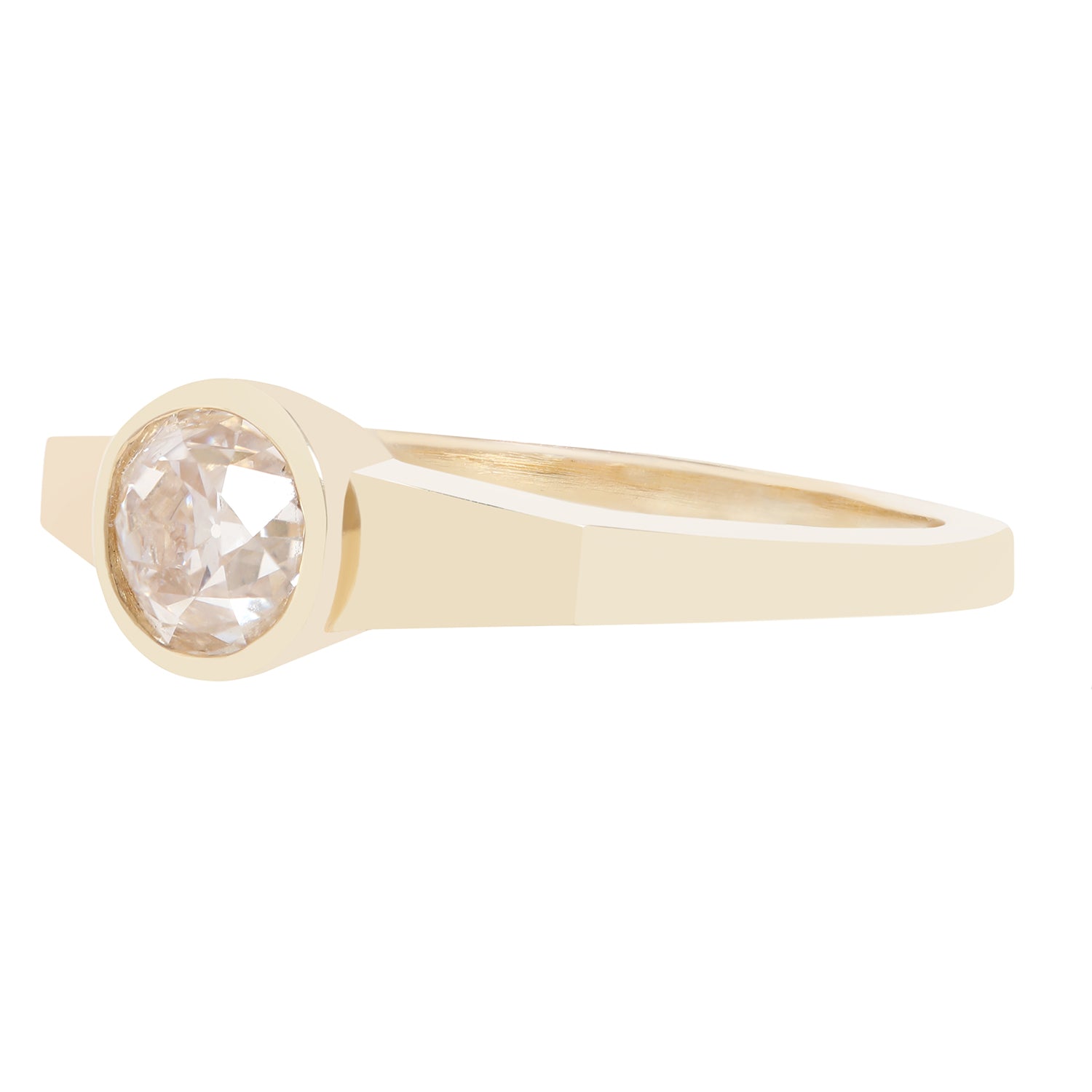 A minimalist yellow gold ring featuring a bezel-set round-cut clear diamond, presented on a solid white background.