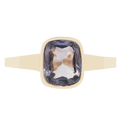 Bezel set solitaire yellow gold ring with a dark blue spinel rectangular stone on white background. 