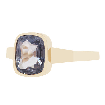 Bezel set solitaire yellow gold ring with a dark blue spinel rectangular stone on white background. 