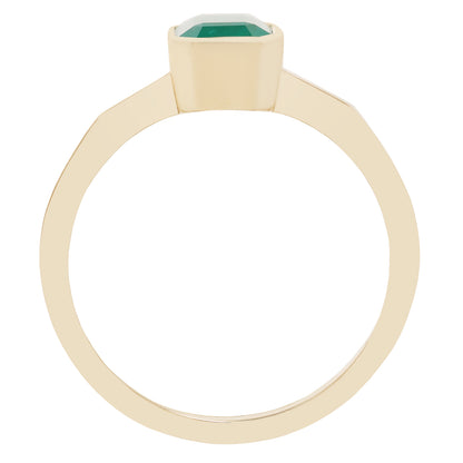 A close-up of a gold ring with a rectangular green gemstone, set against a plain white background.