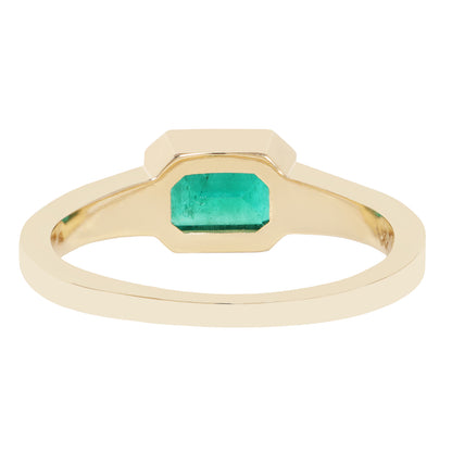 A yellow gold ring featuring a large, faceted emerald-cut green gemstone in a bezel setting, shown against a plain white background.