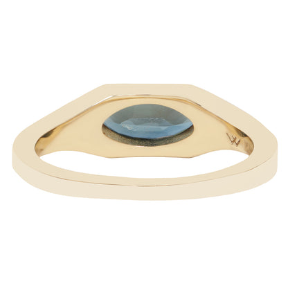 A gold ring with a wide, geometric triangular-shaped setting and a central oval-cut light blue gemstone, shown on a plain white background.