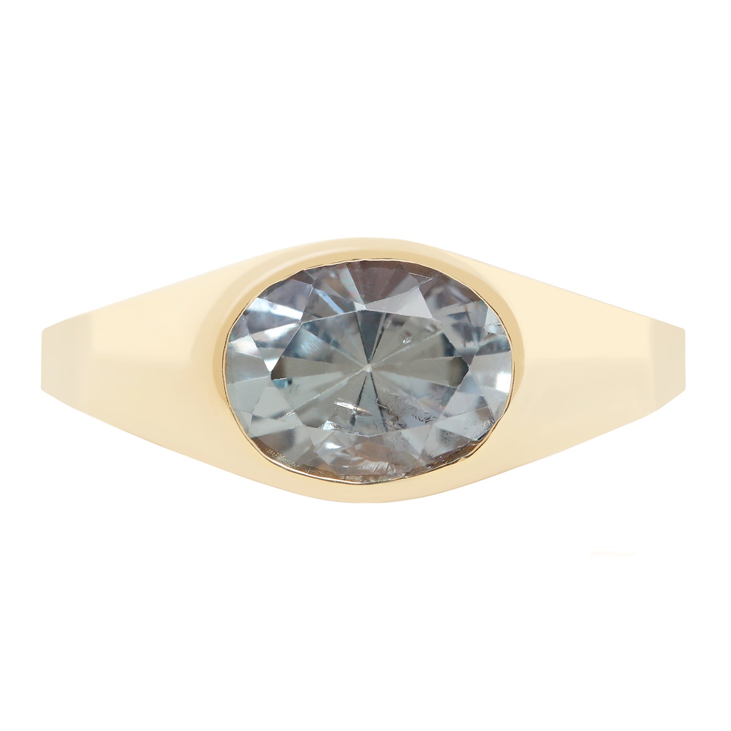 A yellow gold signet ring featuring a large, oval-cut light blue-gray gemstone, shown against a plain white background.