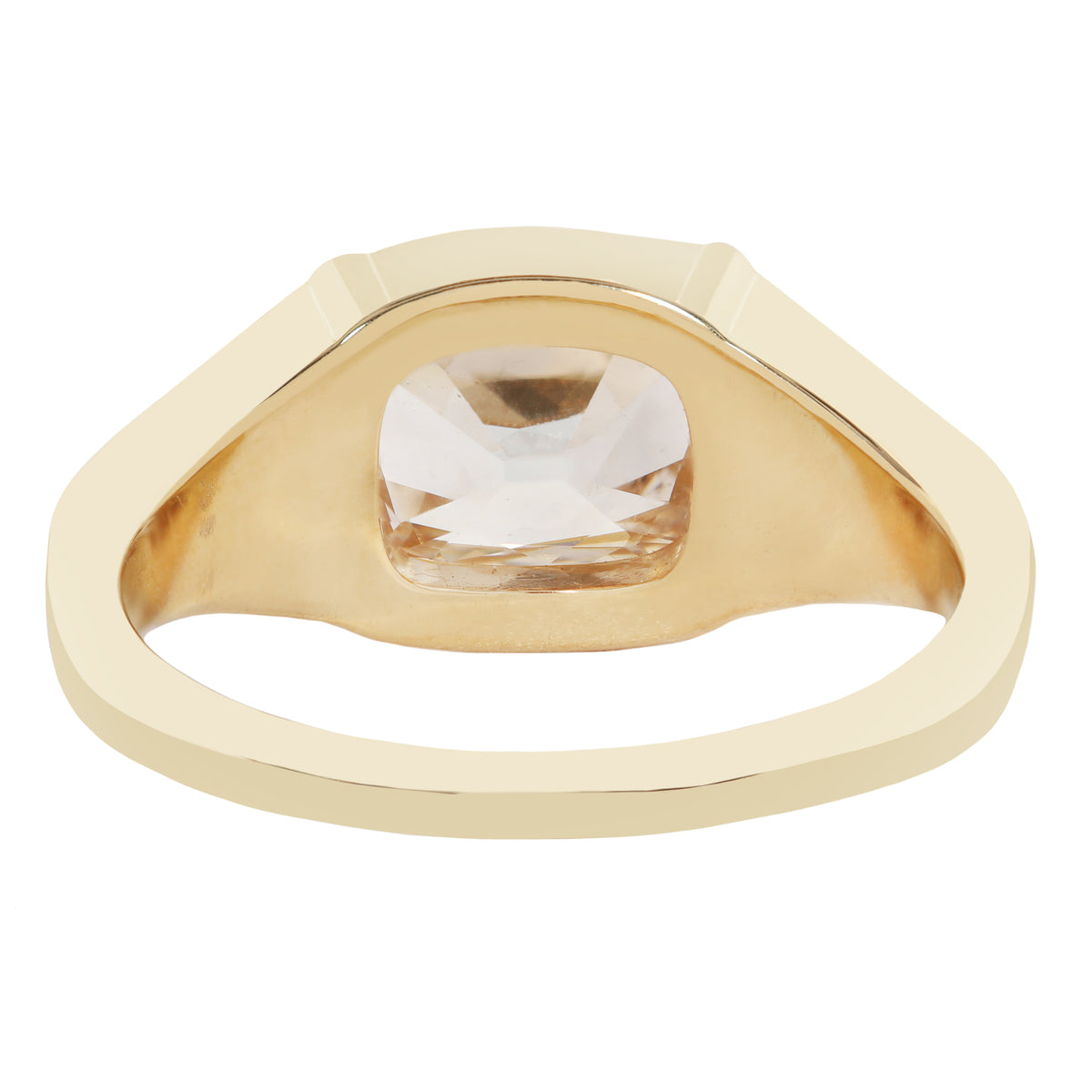A gold signet-style ring with a large, bezel-set clear cushion-cut gemstone, shown on a plain white background.
