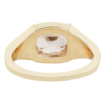 A gold signet-style ring with a large, bezel-set clear cushion-cut gemstone, shown on a plain white background.