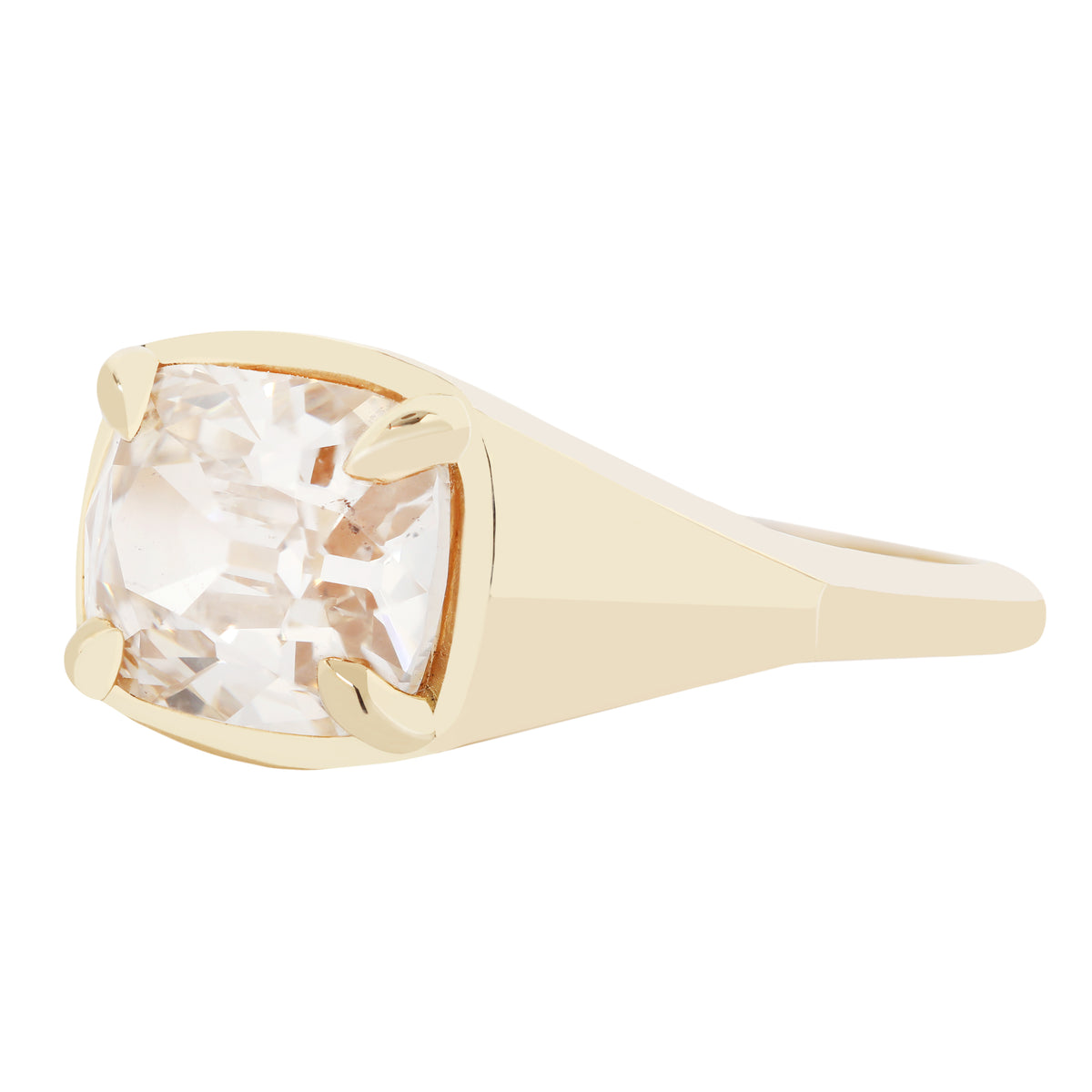 A yellow gold signet ring featuring a large cushion-cut clear gemstone in a four-prong setting, shown on a plain white background.