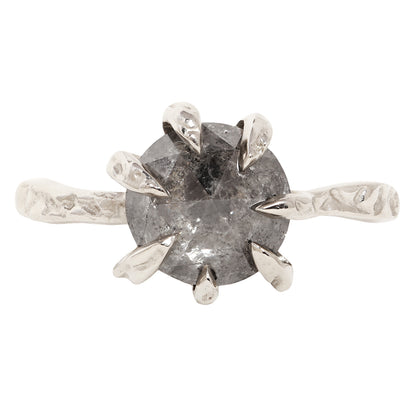 A unique white gold ring featuring a large, round, faceted gray gemstone held in a six-prong setting with textured, leaf-like prongs, mounted on a matching textured band.