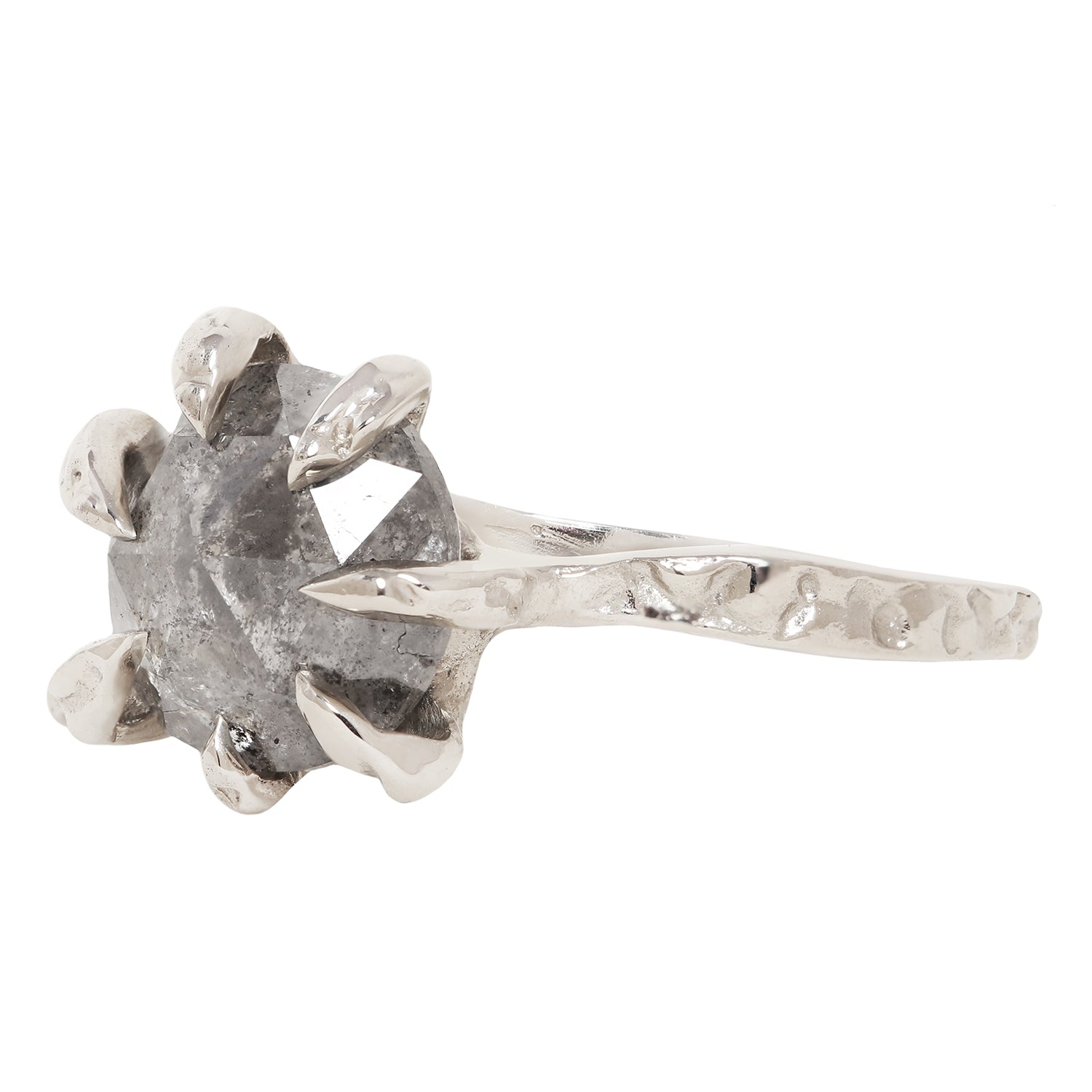A white gold ring featuring a rough, faceted gray gemstone in a claw setting with a textured, organic-shaped band, shown against a plain white background.