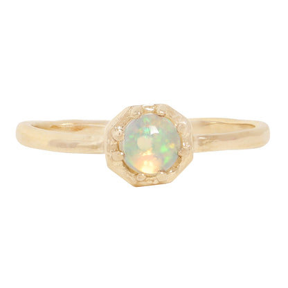 A gold ring featuring a round iridescent opal gemstone in a textured prong octagon setting, shown against a plain white background.