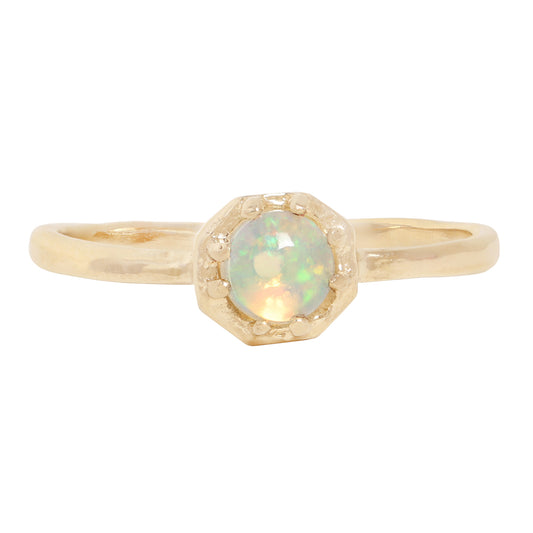 A gold ring featuring a round iridescent opal gemstone in a textured prong octagon setting, shown against a plain white background.