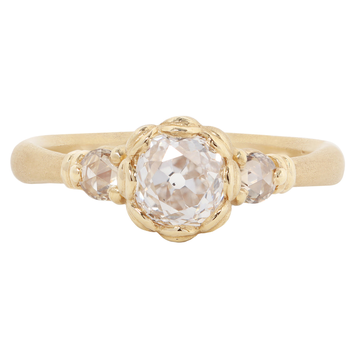 A gold ring featuring a large, round-cut clear gemstone surrounded by a decorative border of small gold beads, set on a smooth gold band against a plain white background.