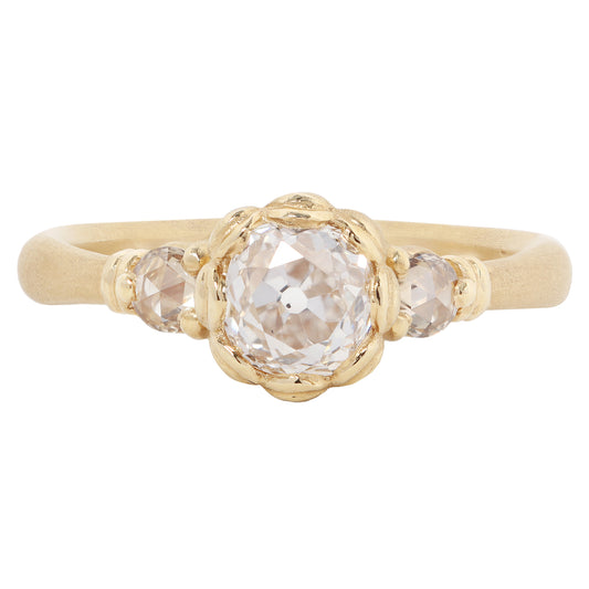 A gold ring featuring a large, round-cut clear gemstone surrounded by a decorative border of small gold beads, set on a smooth gold band against a plain white background.