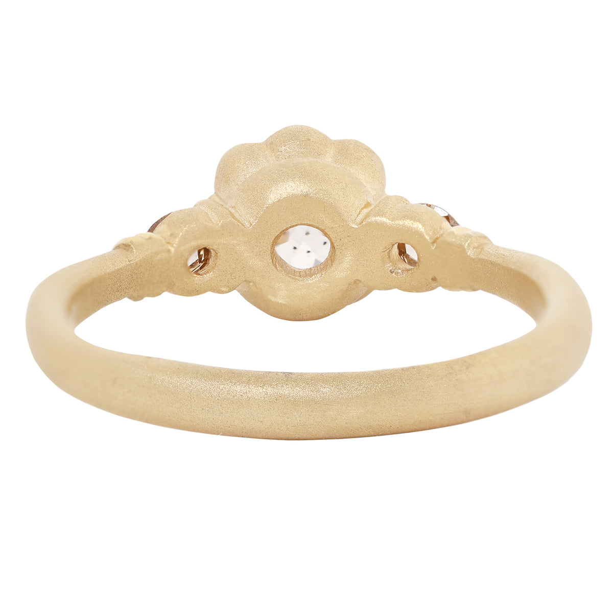 Back view of a gold ring featuring a large, round-cut clear gemstone surrounded by a decorative border of small gold beads, set on a smooth gold band against a plain white background.