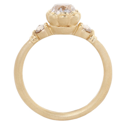 A gold ring featuring a large, round-cut clear gemstone surrounded by a decorative border of small gold beads, set on a smooth gold band against a plain white background.