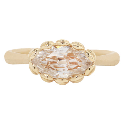 A gold ring featuring a large, oval-cut clear gemstone surrounded by a decorative border of small gold beads, set on a smooth gold band against a plain white background.