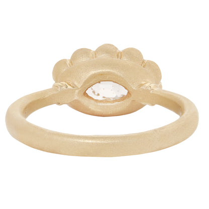 A textured yellow gold ring featuring a scalloped eye-shaped bezel with a clear, faceted gemstone in the center, set against a plain white background.