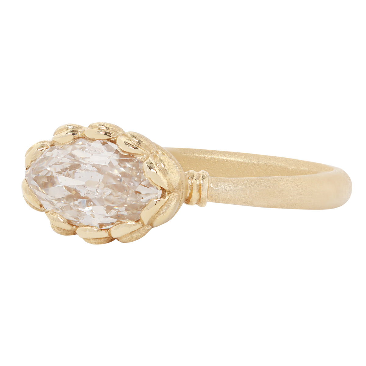 A yellow gold ring featuring a large, oval-cut clear gemstone in a textured, leaf-like bezel setting, shown against a plain white background.