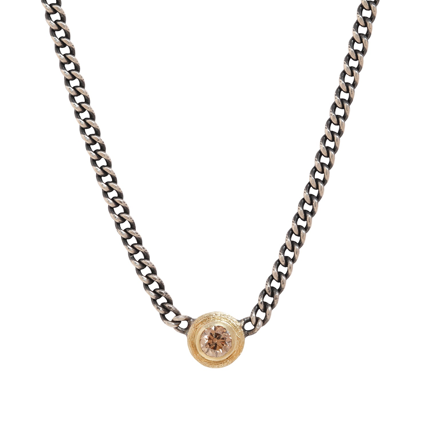 A silver-toned curb chain necklace featuring a small circular gold-toned pendant with a clear faceted gemstone, shown against a plain white background.