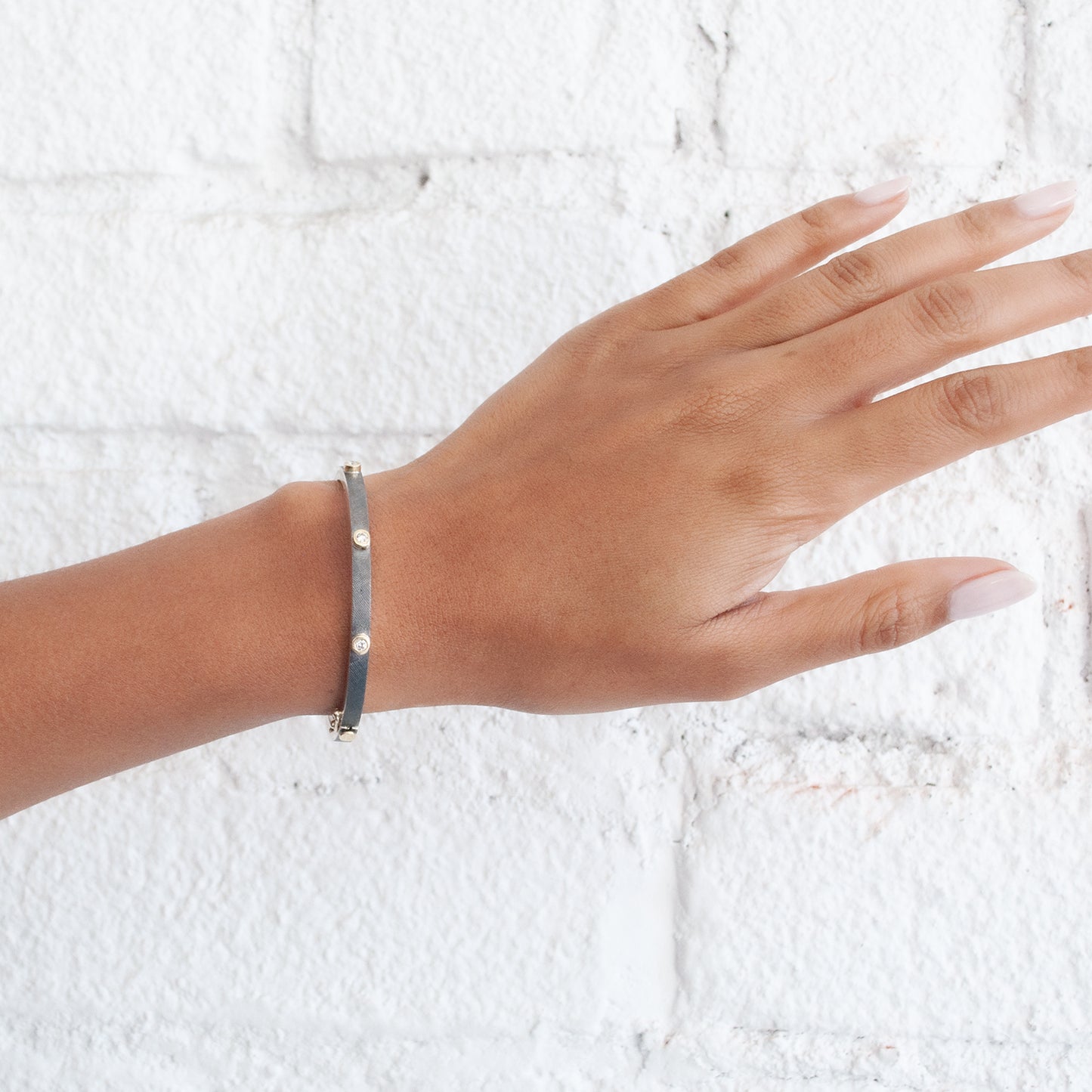 Rene Escobar - Hand wearing a bracelet on a textured white background