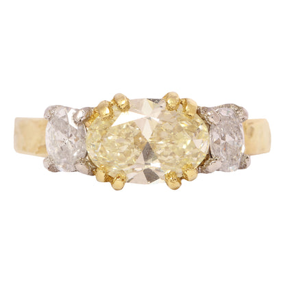 Gold and platinum ring with a central yellow diamond and smaller diamonds on a white background