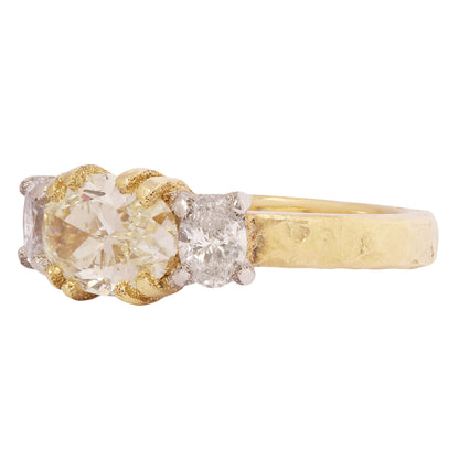 Gold and platinum ring with a central yellow diamond and smaller diamonds on a white background