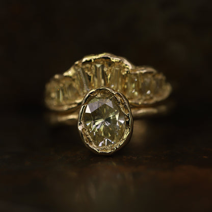 Ellis Mhairi Cameron - Gold ring with a large diamond and smaller diamonds on a dark background