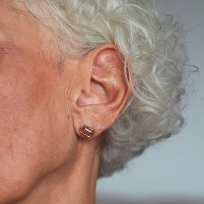 Ellis Mhairi Cameron - Close-up of an older woman's ear with a gold earring against a neutral background