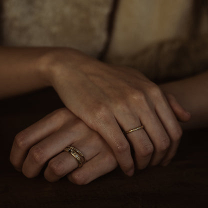 Ellis Mhairi Cameron - Close-up of hands with gold rings on a dark background