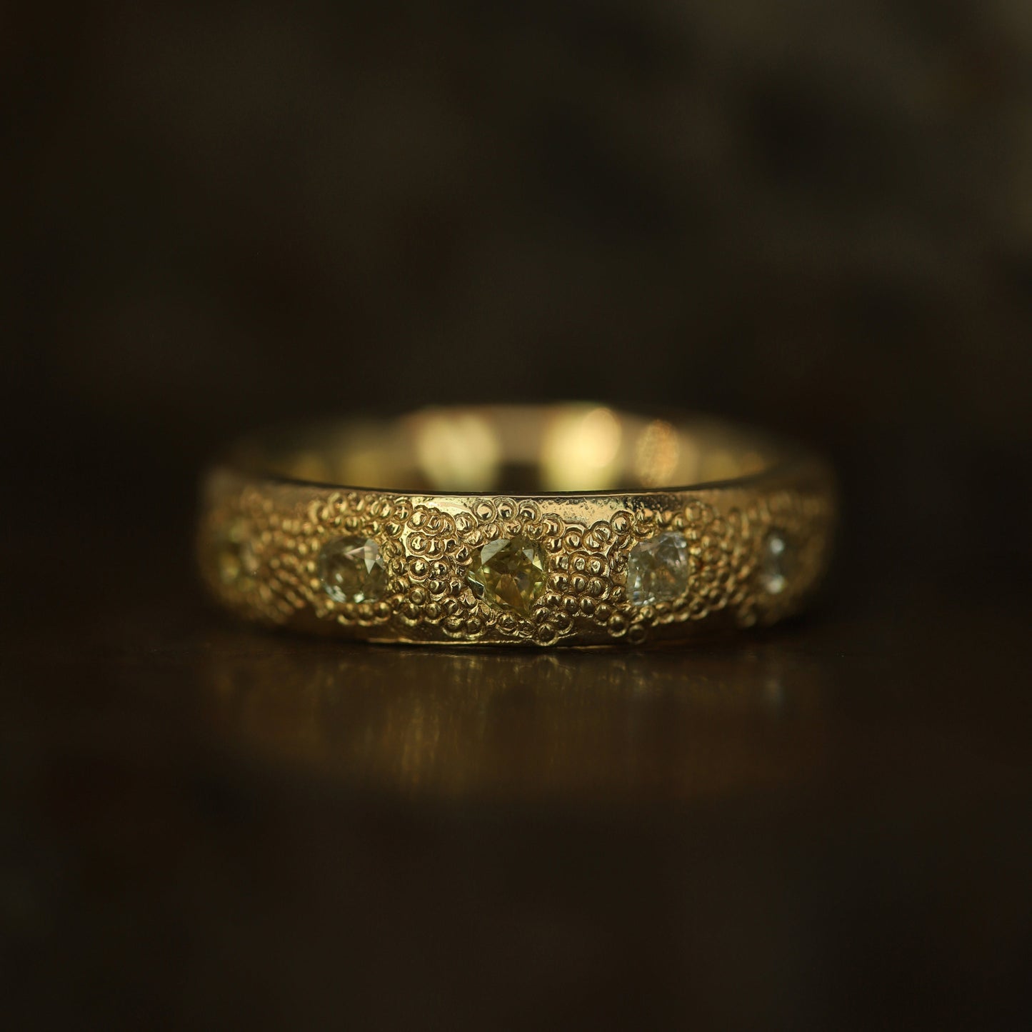Gold ring with intricate design on a dark background