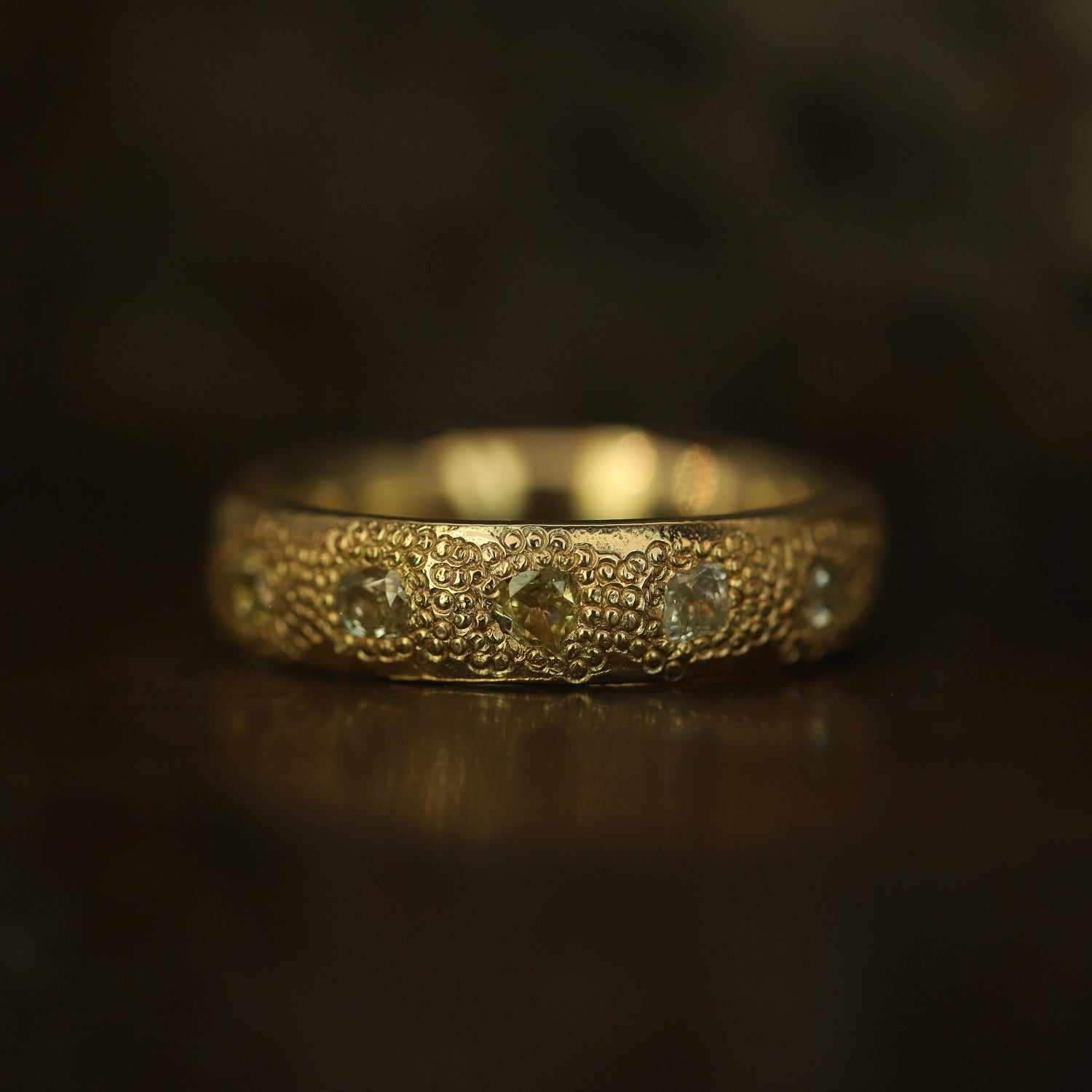 Gold ring with intricate design on a dark background