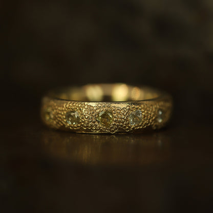 Gold ring with intricate design on a dark background