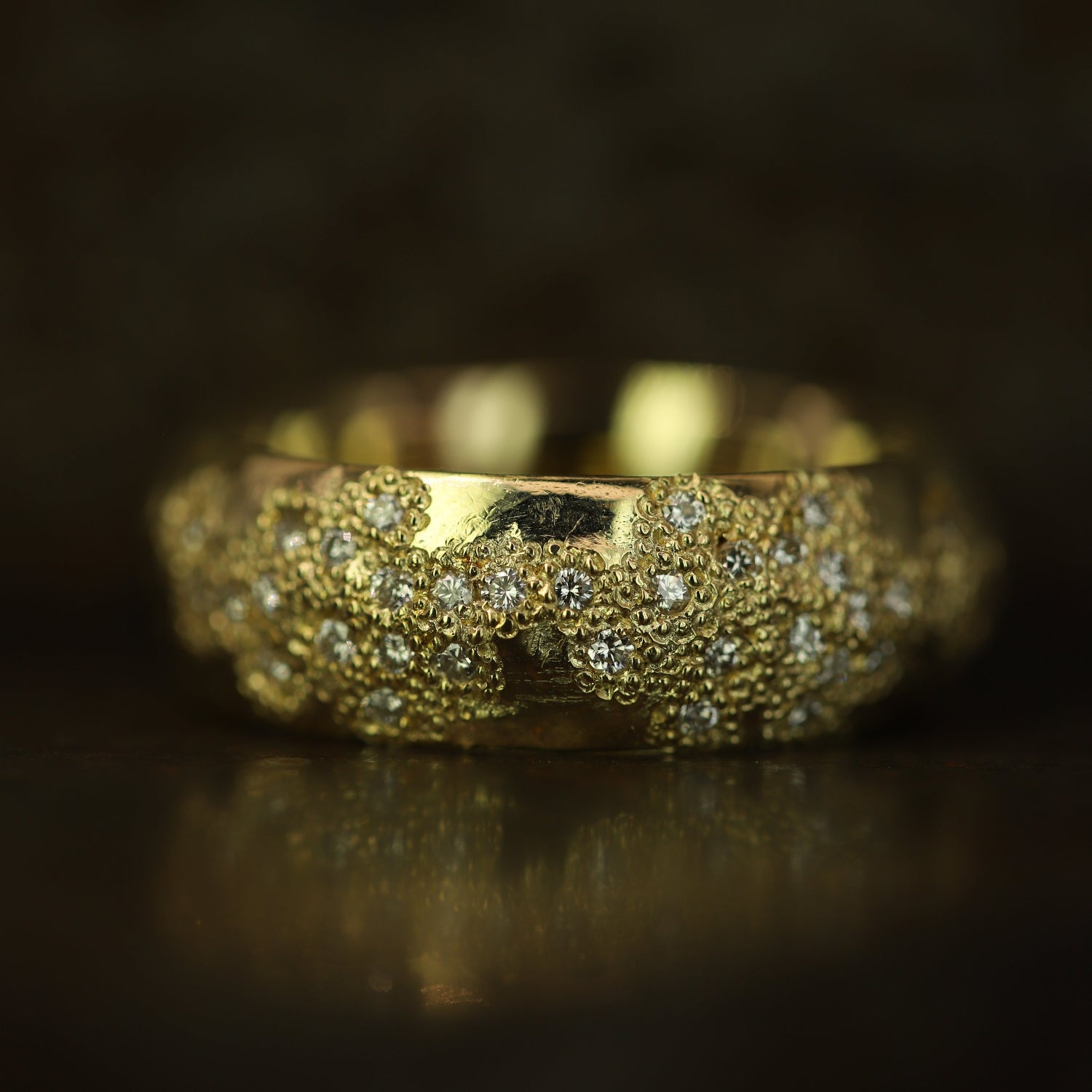 Ellis Mhairi Cameron - Gold ring with textured band and embedded stones on a dark background