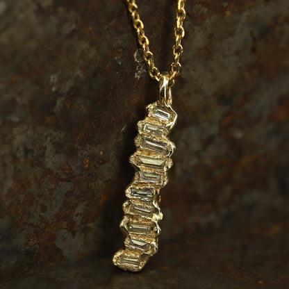 Ellis Mhairi Cameron - Gold necklace with a diamond pendant on a textured brown background