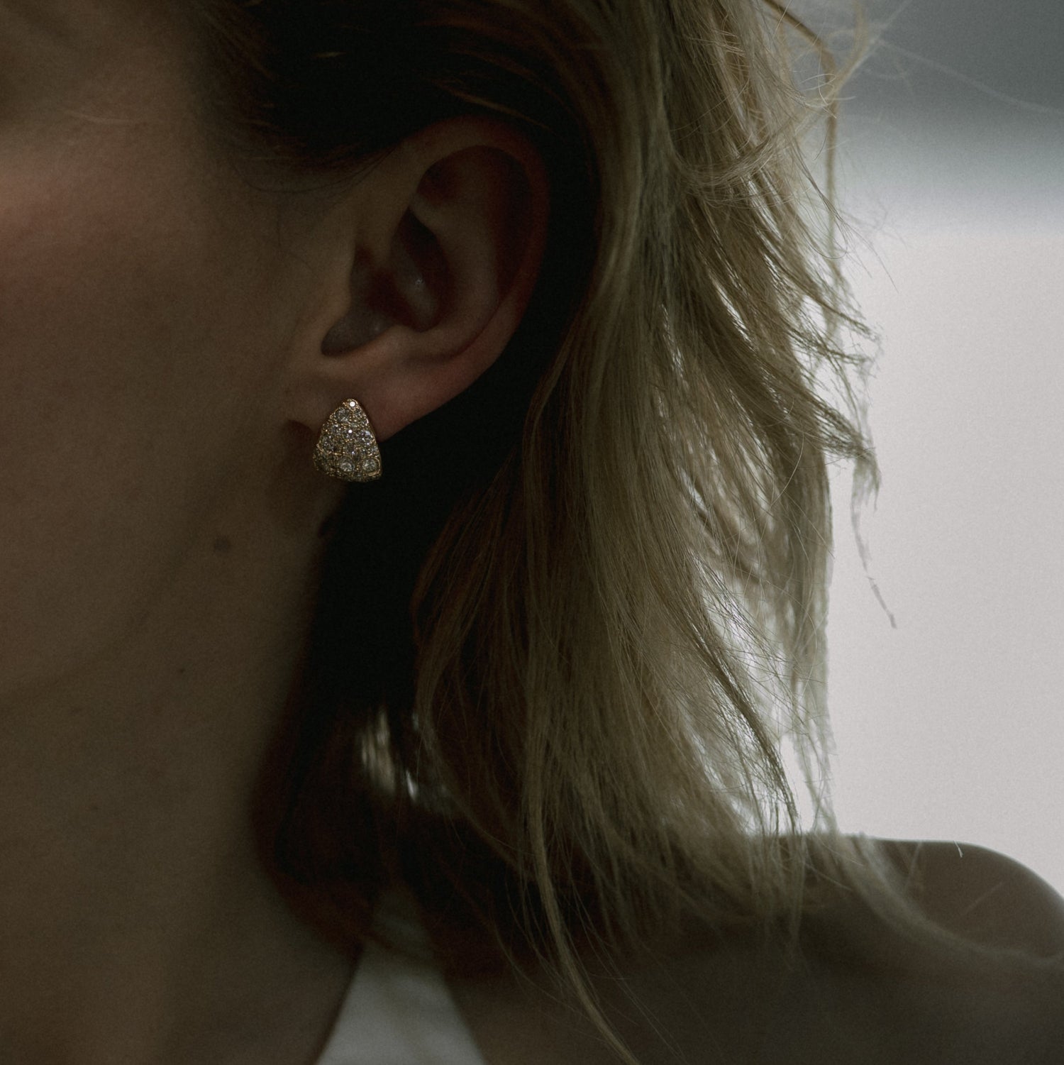 Ellis Mhairi Cameron - Close-up of an ear wearing a gold earring with blurred background
