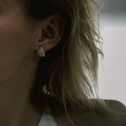 Ellis Mhairi Cameron - Close-up of an ear wearing a gold earring with blurred background