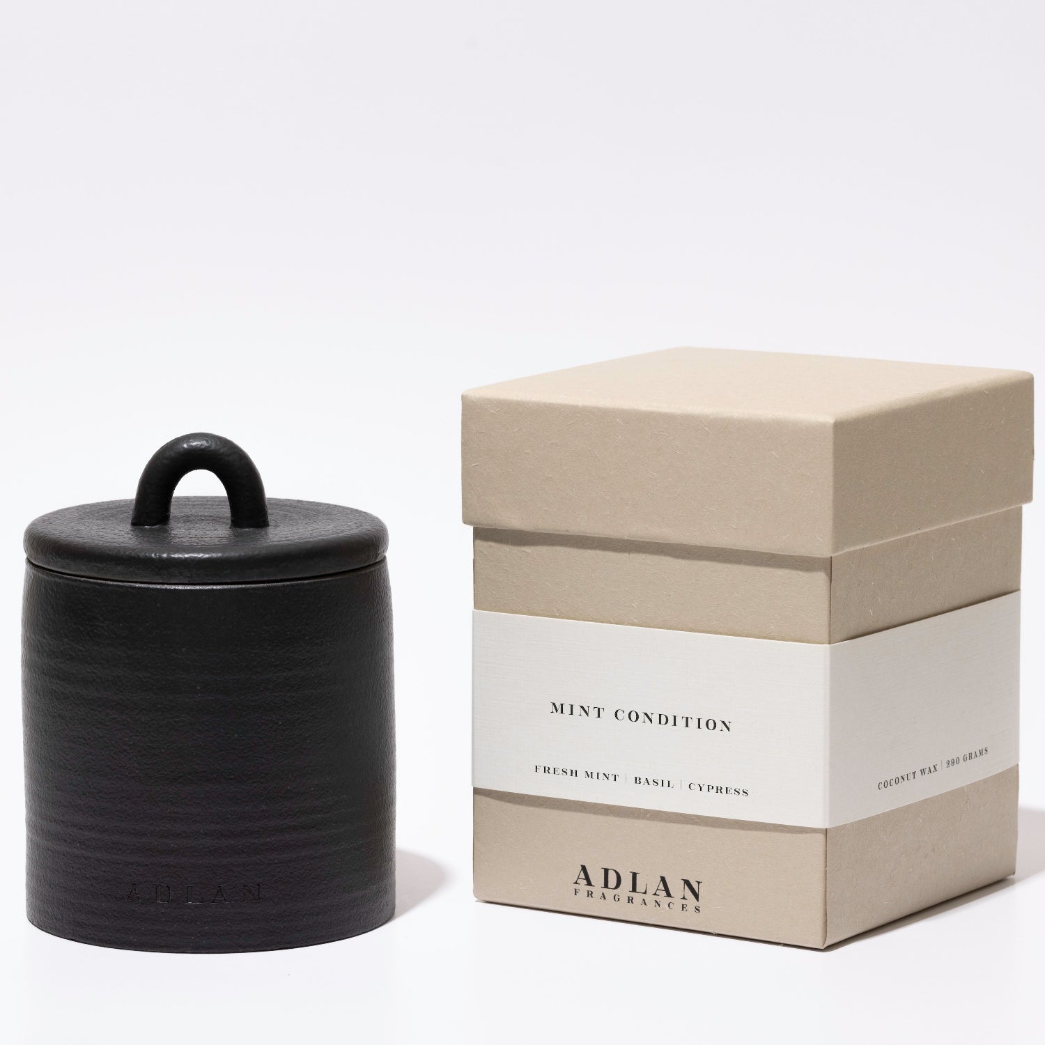A black ceramic jar candle with a lid and loop handle, displayed next to its beige and white packaging box labeled 'MINT CONDITION' and 'ADLAN COLLECTIONS' on a clean white background.